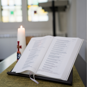 Opengeslagen Bijbel en paaskaars in een kerk