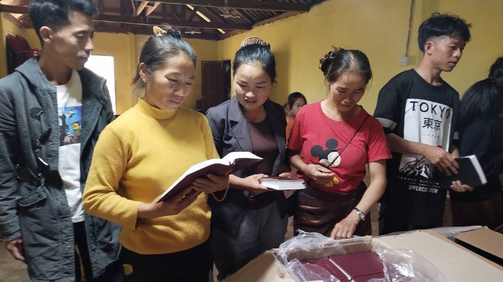 Kerkgangers in Laos bekijken de nieuwe Bijbels.