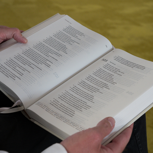 Man heeft een opengeslagen Bijbel op schoot liggen en leest.