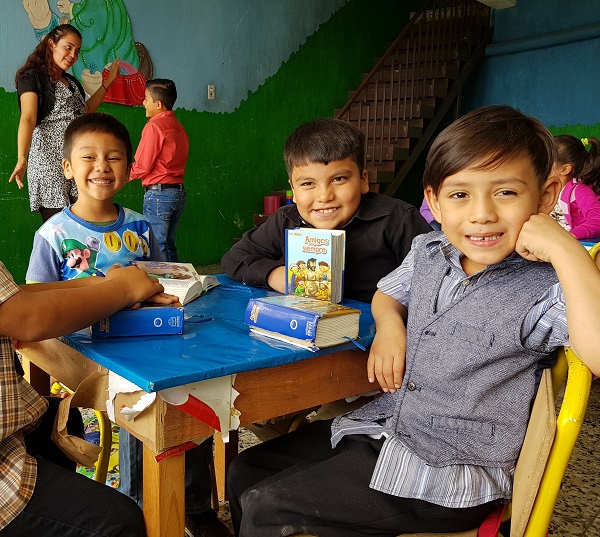 Drie jongens aan tafel tijdens een Grow and Learn bijeenkomst. Ze hebben elk een eigen Bijbel voor zich.