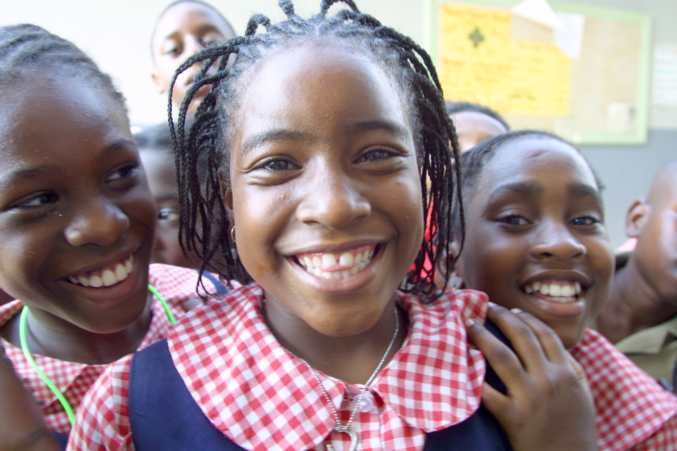 Drie meisjes in Jamaica in schooluniform, de middelste kijkt direct in de camera.