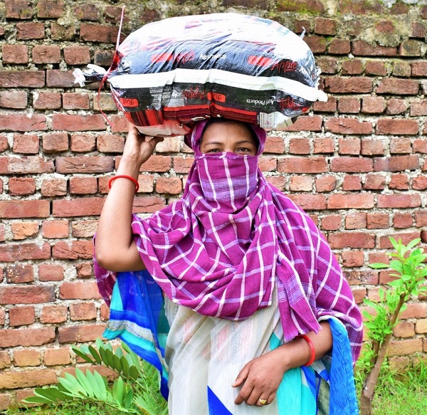 Weduwe in India met een pakket voedsel op haar hoofd.
