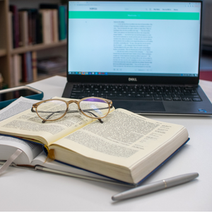 Een stapel boeken waarmee de Bijbel vertaald kan worden en een laptop