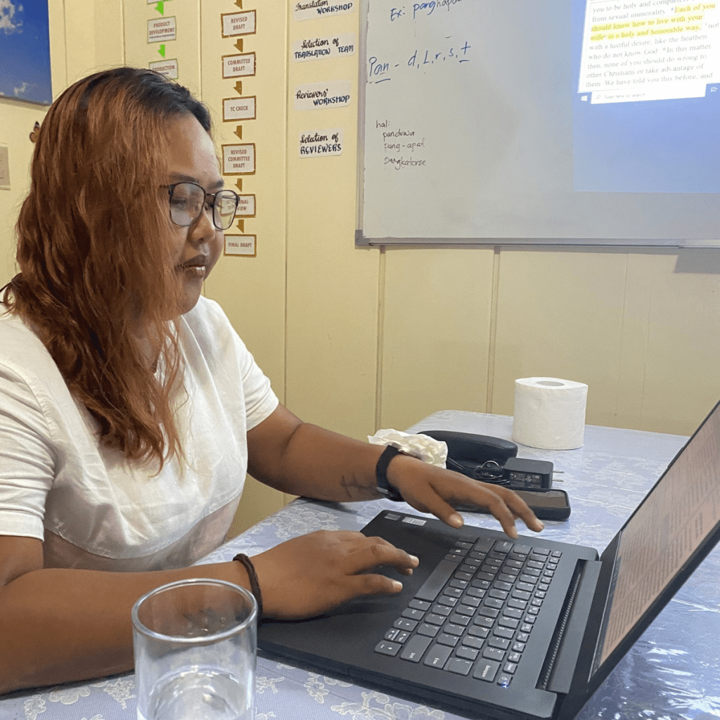 Bijbelvertaler (vrouw) werkt op laptop.