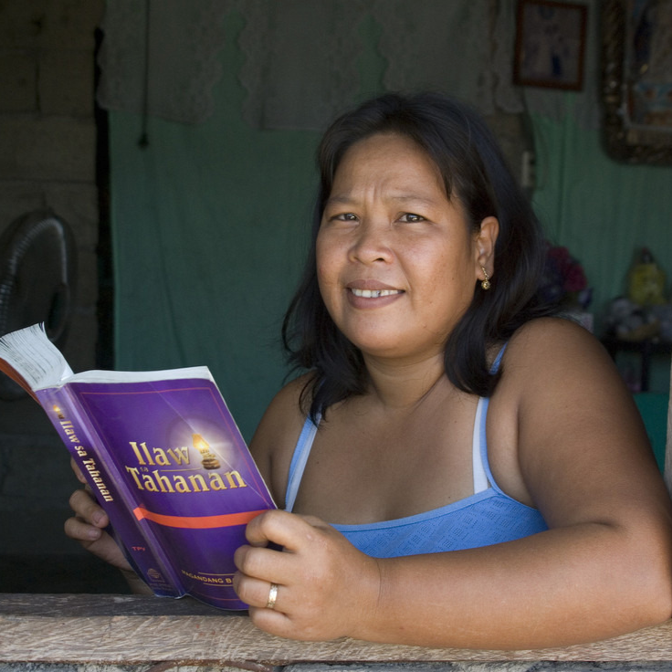 Filipijnse vrouw houdt Bijbel vast en kijkt in camera.