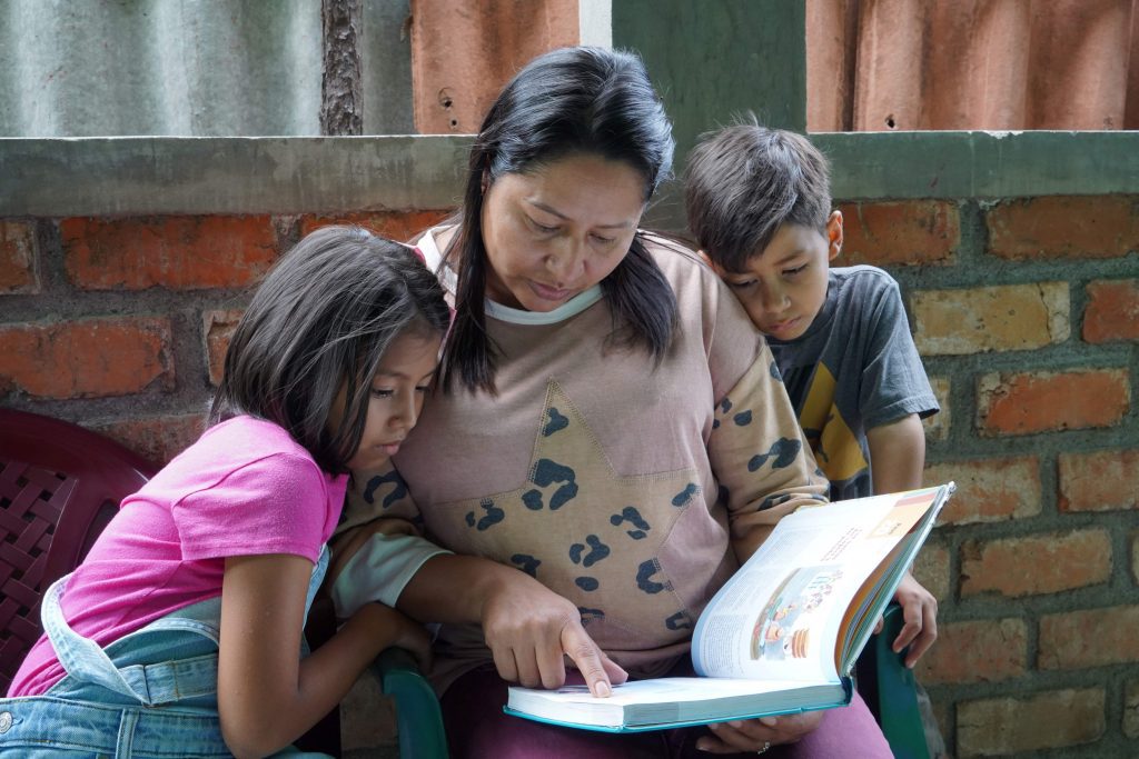 Een moeder leest haar dochter en zoon voor uit de Samenleesbijbel.