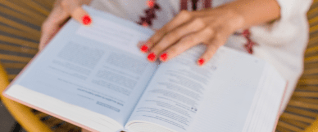 Vrouw met rode nagellak leest uit de Bijbel