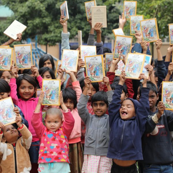Een groep Bengalese kinderen houden vrolijk hun Bijbel in de lucht