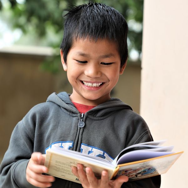 Bengalese jongen kijkt lachend in zijn open Bijbel
