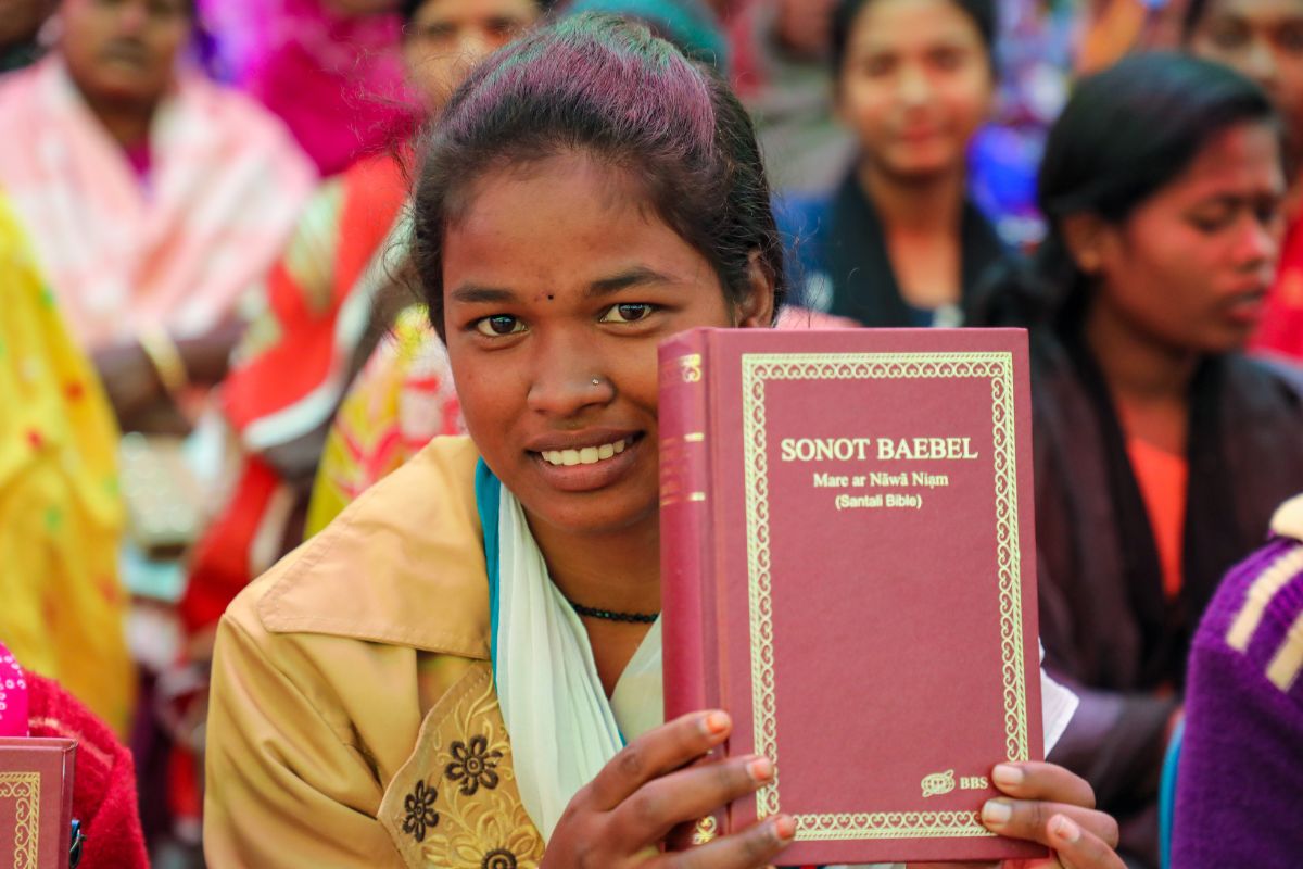 Bengalese vrouw laat haar Bijbel zien aan de kijker, ze lacht verlegen